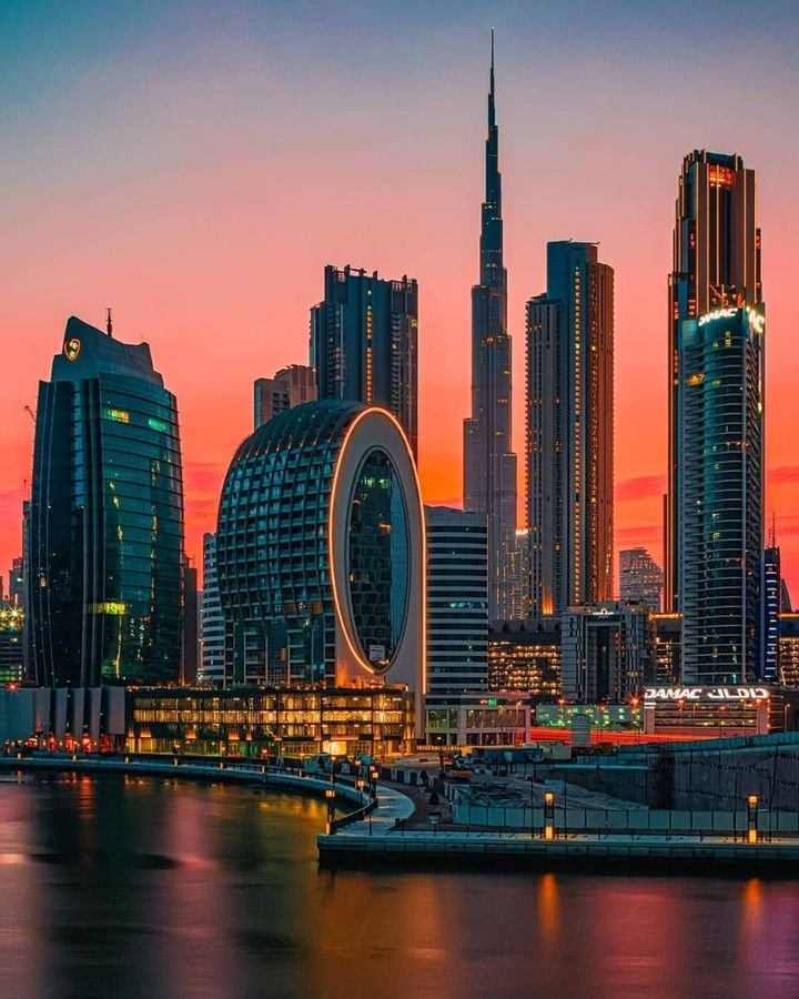 Business Bay towers and the Dubai Water Canal against a sunset sky