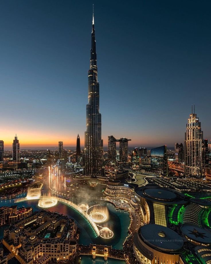Burj Khalifa rising above the illuminated Dubai Fountain at dusk
